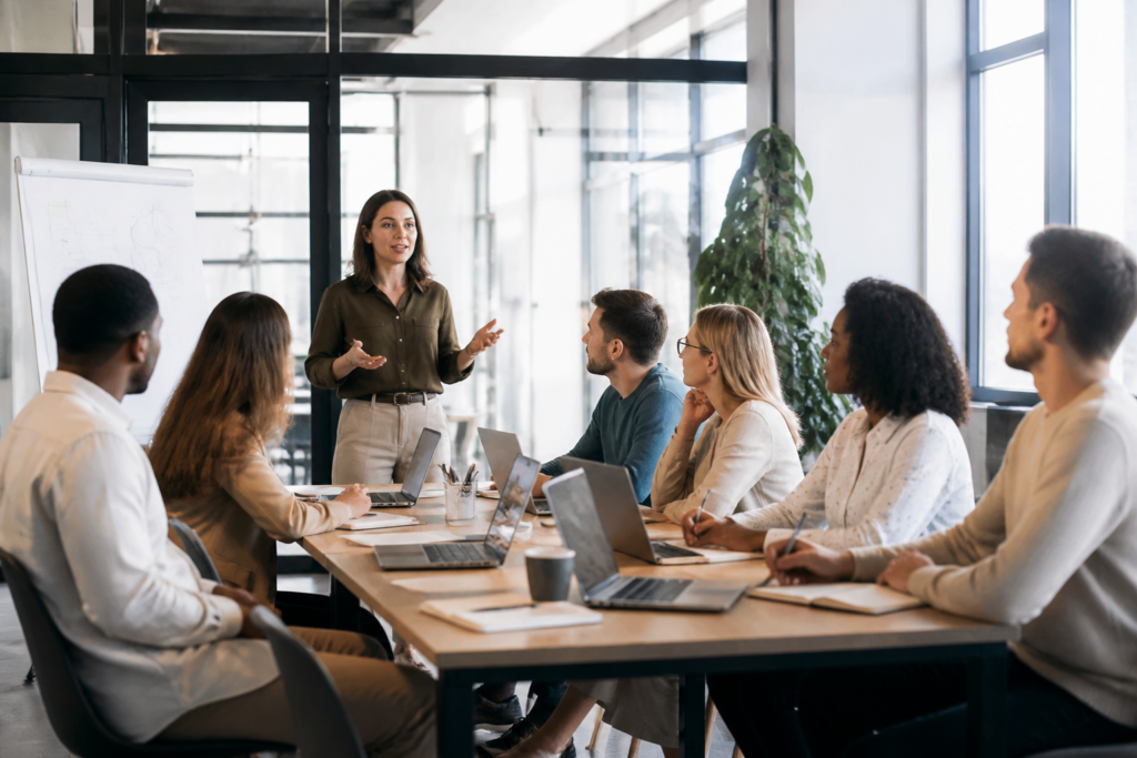 Groupe de personnes en formation dans un bureau moderne avec ordinateurs et carnets