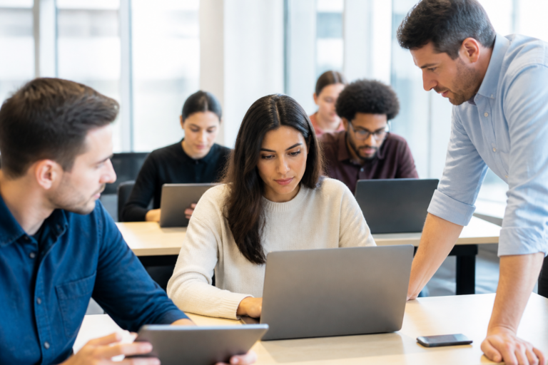 Groupe de personnes en formation informatique avec tablettes et ordinateurs dans une salle moderne