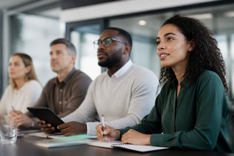 Groupe de personnes en formation professionnelle en salle de réunion avec carnets et tablettes