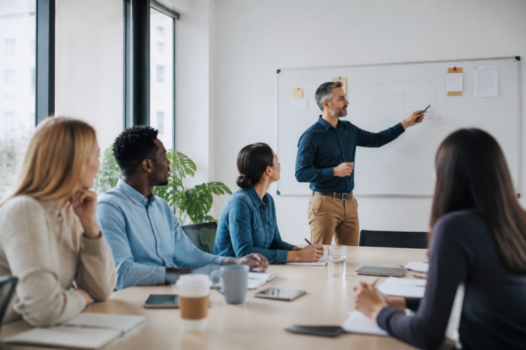 Professionnels en formation dans un bureau moderne collaborant autour d’un tableau blanc