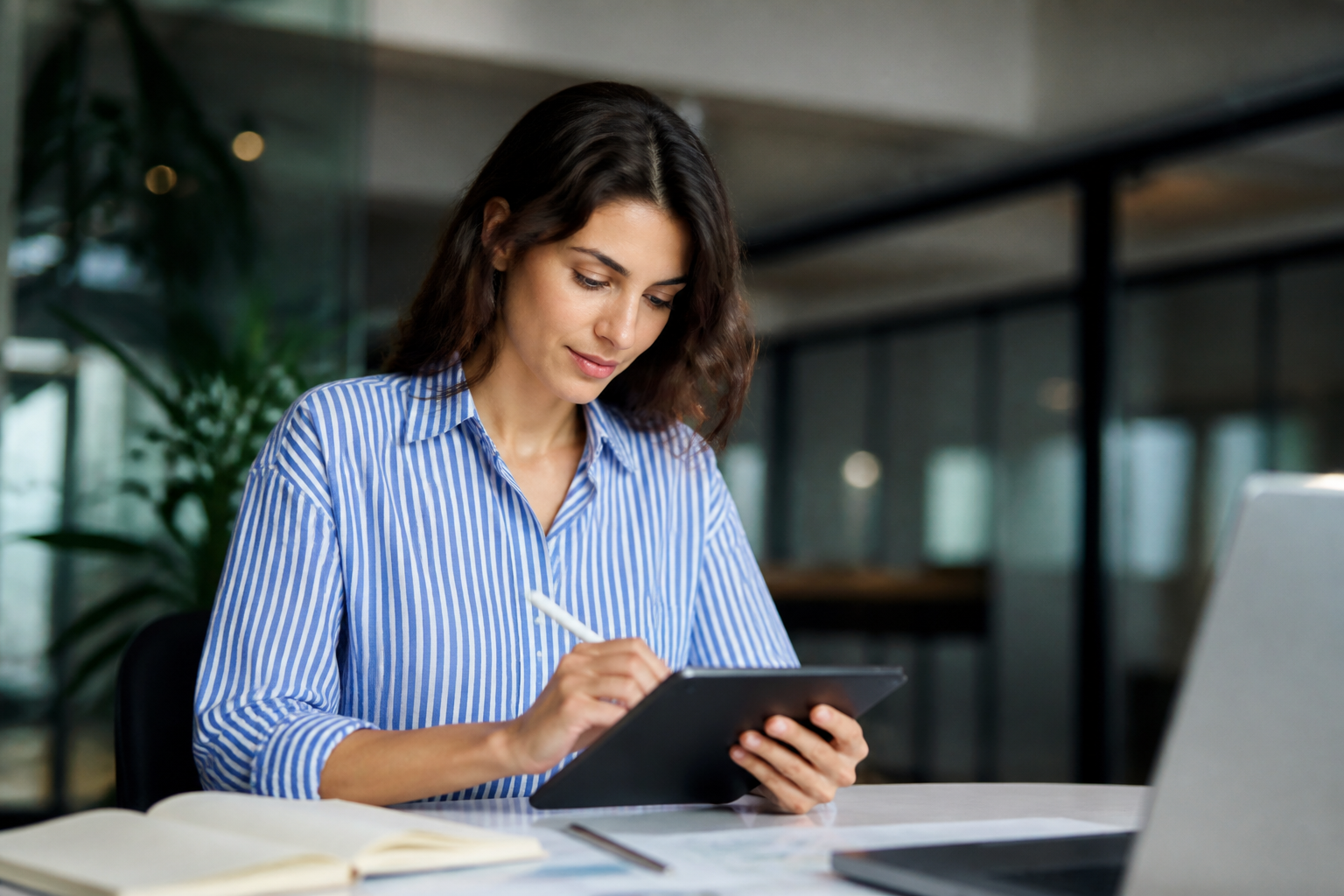 Personne utilisant une tablette numérique avec carnet de notes dans un bureau moderne