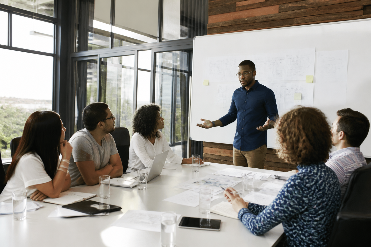 Manager en réunion avec son équipe, utilisant un tableau blanc pour expliquer