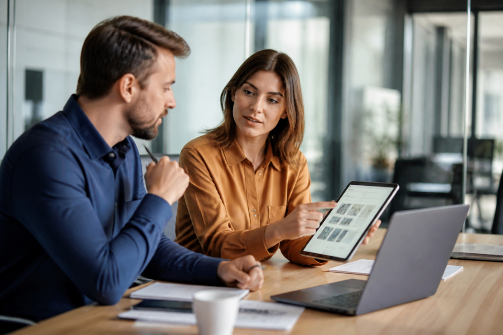 Professionnels échangeant autour d’un plan de formation sur tablette en environnement de bureau moderne